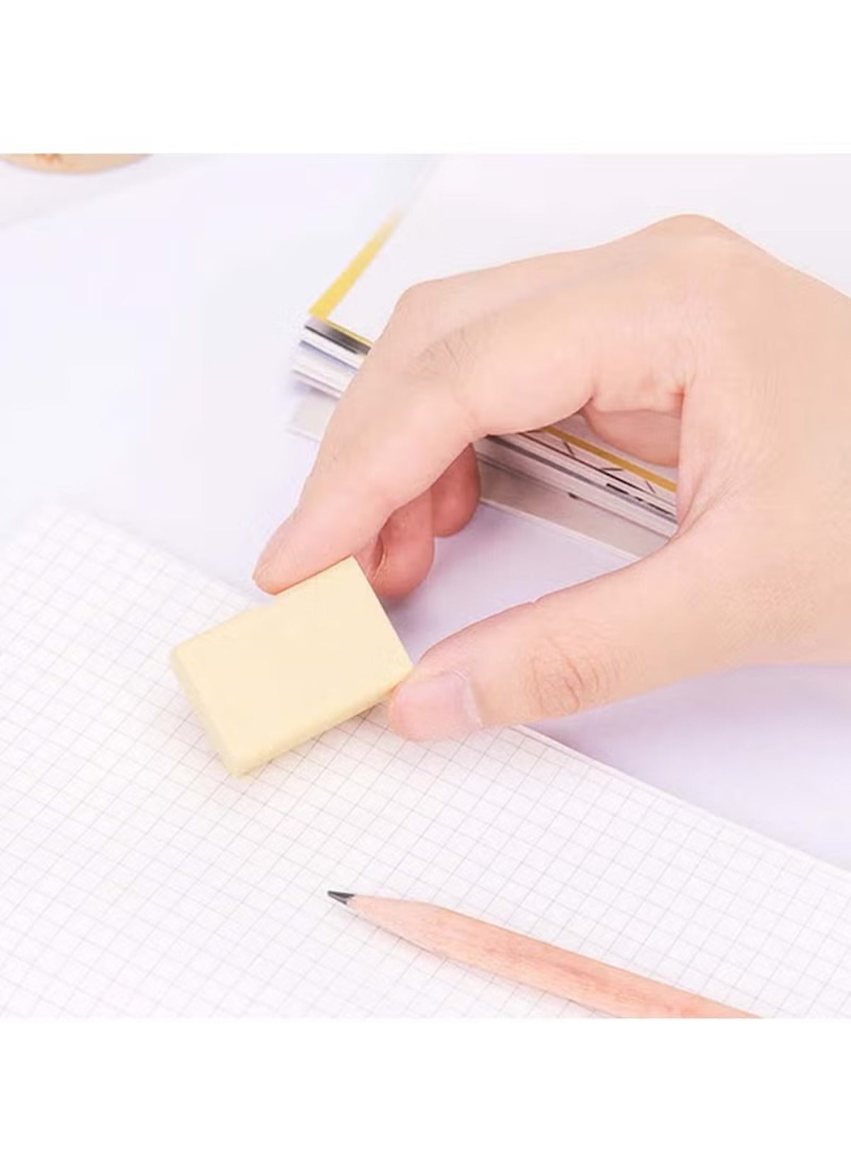 Hand holding eraser cleaning pencil marks on grid paper with 4B art erasers bulk pack Hand holding eraser cleaning pencil marks on grid paper with 4B art erasers bulk pack