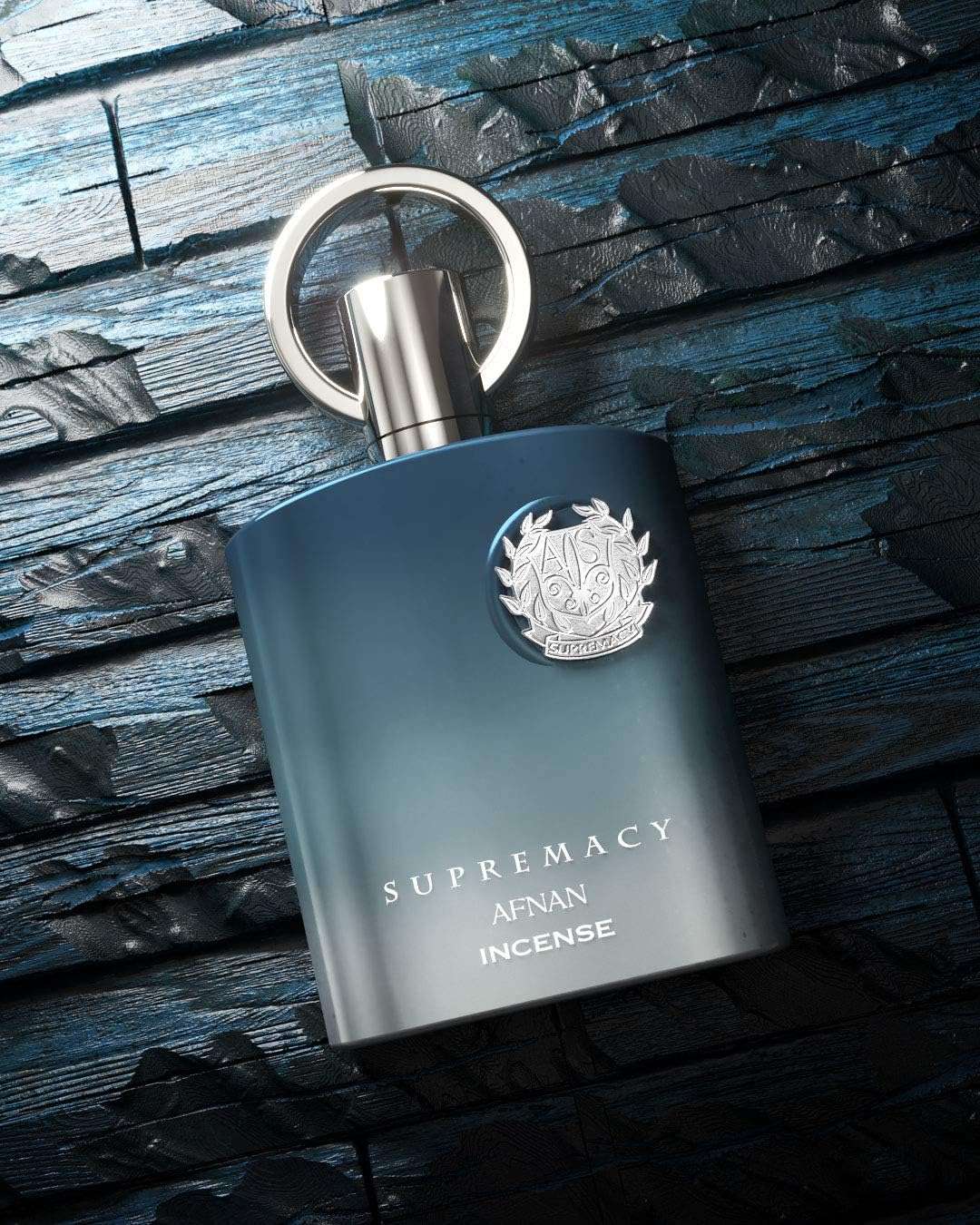 Supremacy Afnan Incense unisex luxury eau de parfum 100ml bottle on textured dark blue surface Supremacy Afnan Incense unisex luxury eau de parfum 100ml bottle on textured dark blue surface