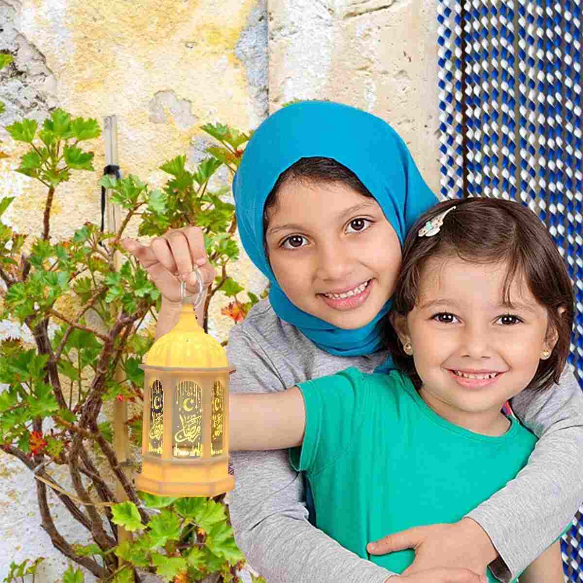 Two smiling children holding a Ramadan LED lantern decoration showing festive lantern light assorted colors Two smiling children holding a Ramadan LED lantern decoration showing festive lantern light assorted colors