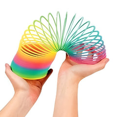 Hands holding a colorful rainbow magic spring toy slinky stretching between them Hands holding a colorful rainbow magic spring toy slinky stretching between them