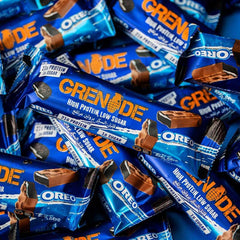 Grenade Oreo protein bars blue wrappers scattered showing high protein low sugar label and chocolate coating Grenade Oreo protein bars blue wrappers scattered showing high protein low sugar label and chocolate coating