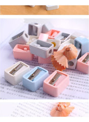 Huitich mini pencil sharpener set with pastel colors including pink, blue, white, and gray on a book page Huitich mini pencil sharpener set with pastel colors including pink, blue, white, and gray on a book page