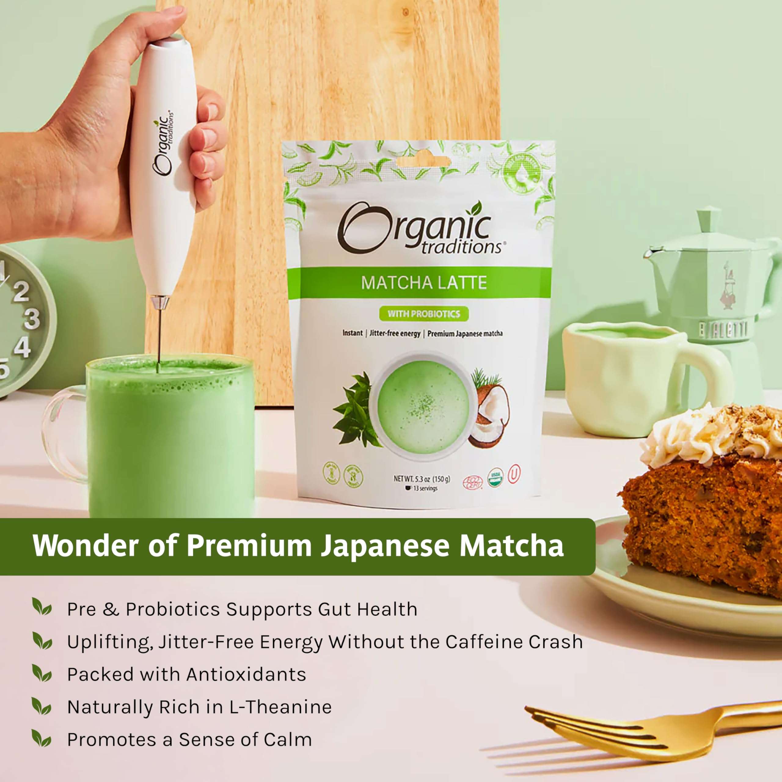 Organic Traditions pouch and frothy cup being whisked with hand frother, slice of cake, organic matcha latte with probiotics Organic Traditions pouch and frothy cup being whisked with hand frother, slice of cake, organic matcha latte with probiotics