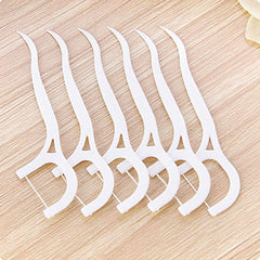 Beibi white plastic dental floss picks 160 pcs. fanned on a wooden surface for daily oral care Beibi white plastic dental floss picks 160 pcs. fanned on a wooden surface for daily oral care