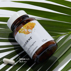 THORNE brown glass bottle and white capsule on palm leaf background Bacillus coagulans probiotic supplement UAE THORNE brown glass bottle and white capsule on palm leaf background Bacillus coagulans probiotic supplement UAE