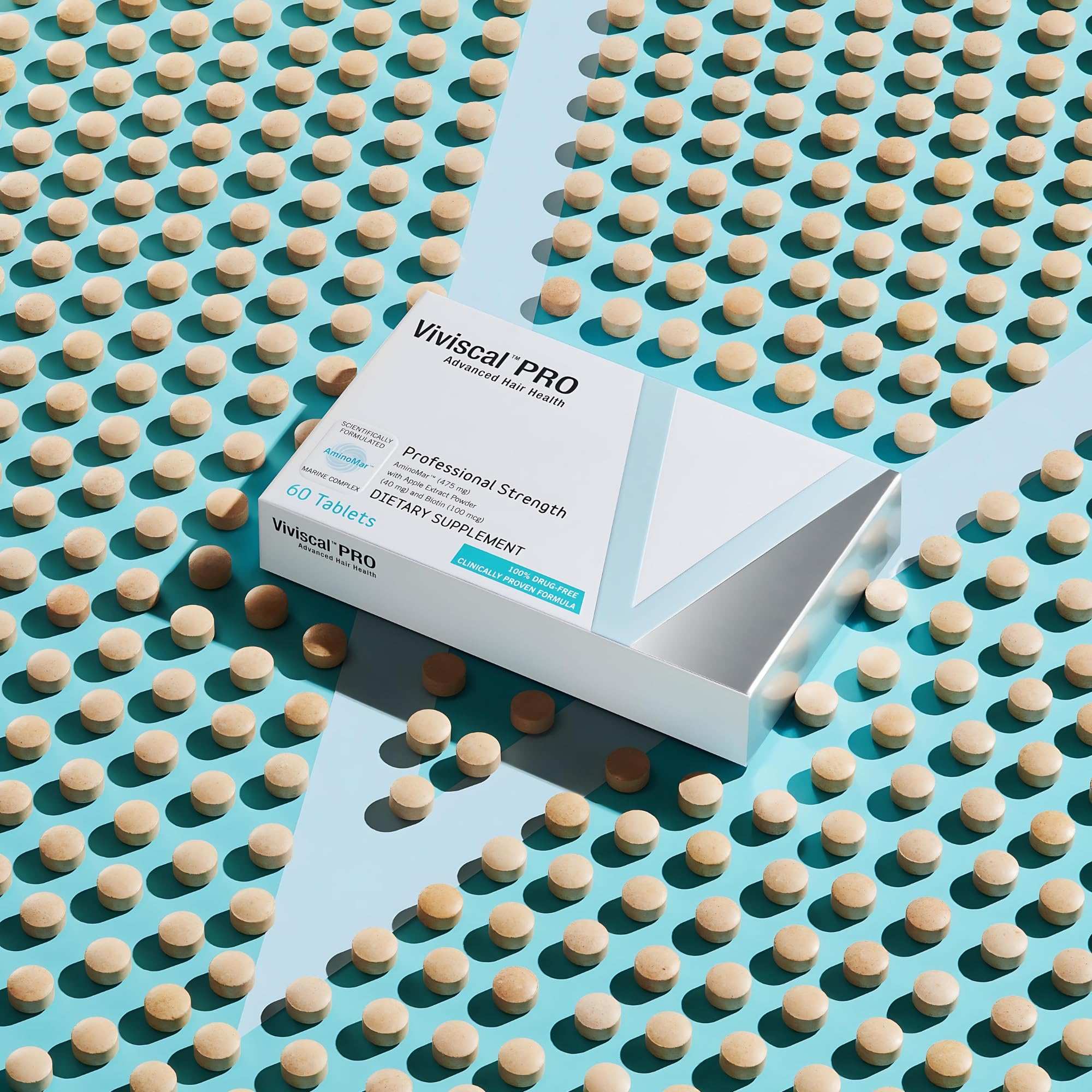 Box of Viviscal PRO hair growth supplements with 60 tablets on teal background surrounded by tablets Box of Viviscal PRO hair growth supplements with 60 tablets on teal background surrounded by tablets