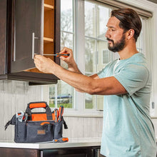 Orange-and-black tool bag with front pockets and straps, shown holding tools on a work surface