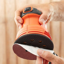 Hands hold an orange random orbit sander showing the circular sanding disc