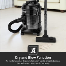 Black drum vacuum cleaner with flexible hose and floor nozzle on light tiles