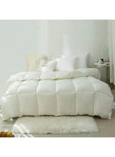 White winter duvet comforter with quilted baffles, neatly arranged on a bed