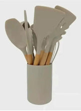 Beige silicone utensil set: assorted spatulas and spoons with wooden handles in holder