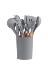 Grey silicone kitchen utensil set with wooden handles in a matching container