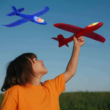Kids light-up airplane glider in red, held overhead; another blue plane flying.