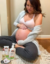 Cocoa butter tummy butter cream containers near pregnant belly on couch