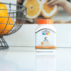 21st Century Vitamin C 500mg tablets white bottle with orange cap on counter beside fresh oranges