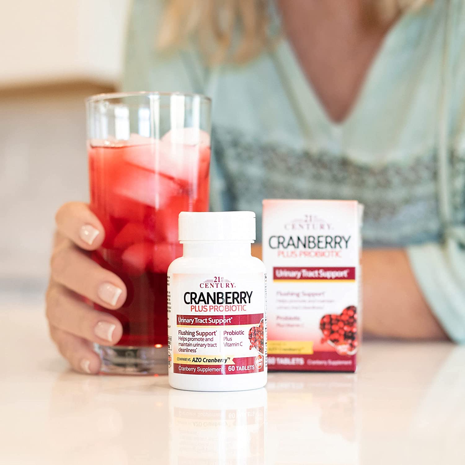 21st Century cranberry probiotics tablets UAE bottle and box on counter with woman holding glass of cranberry drink