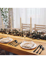 Huitich 24-piece dining flatware set in matte black arranged on a holiday decorated wooden table