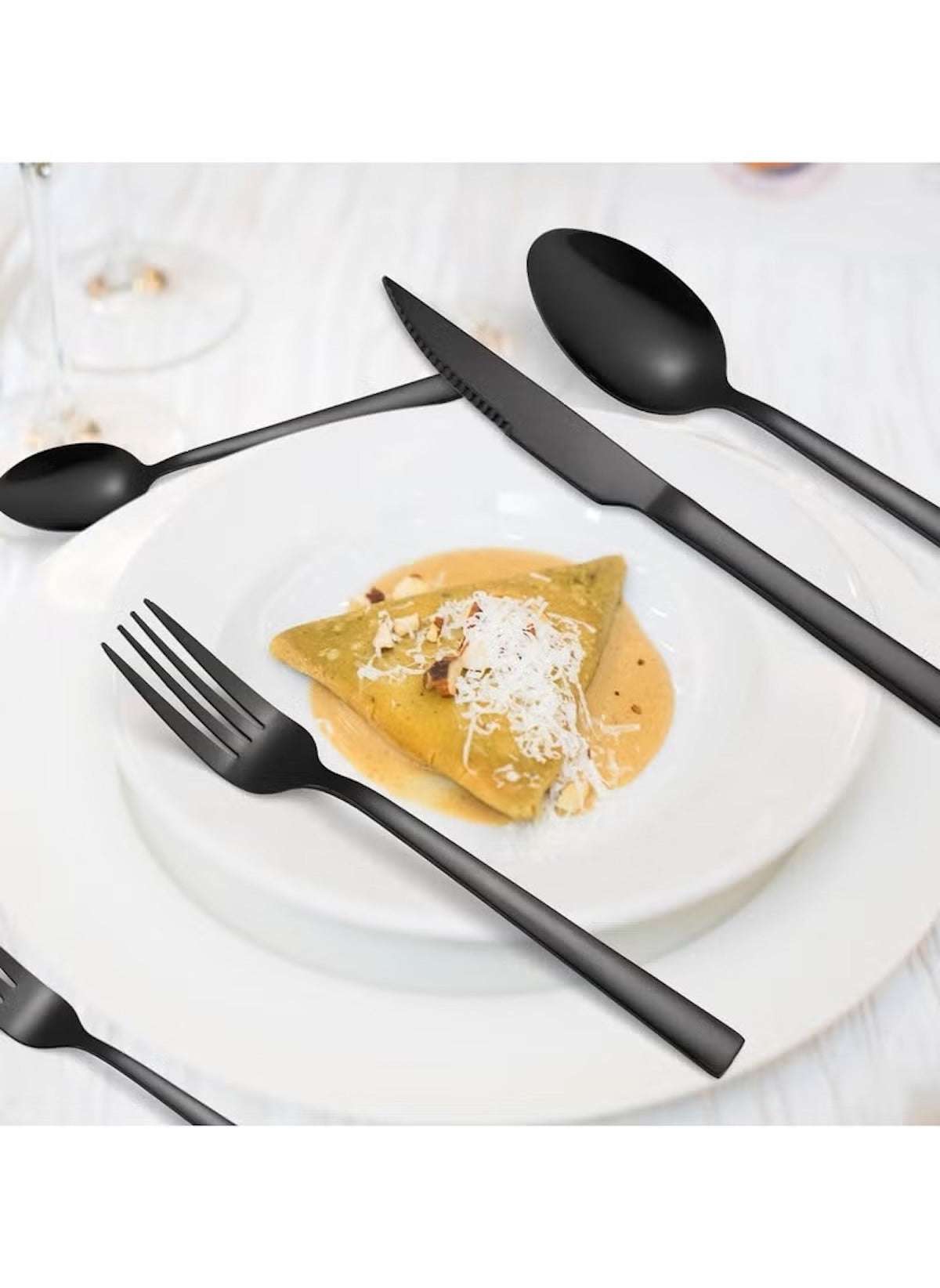 Huitich 24-piece dining flatware set in matte black with fork knife and spoons on white plate