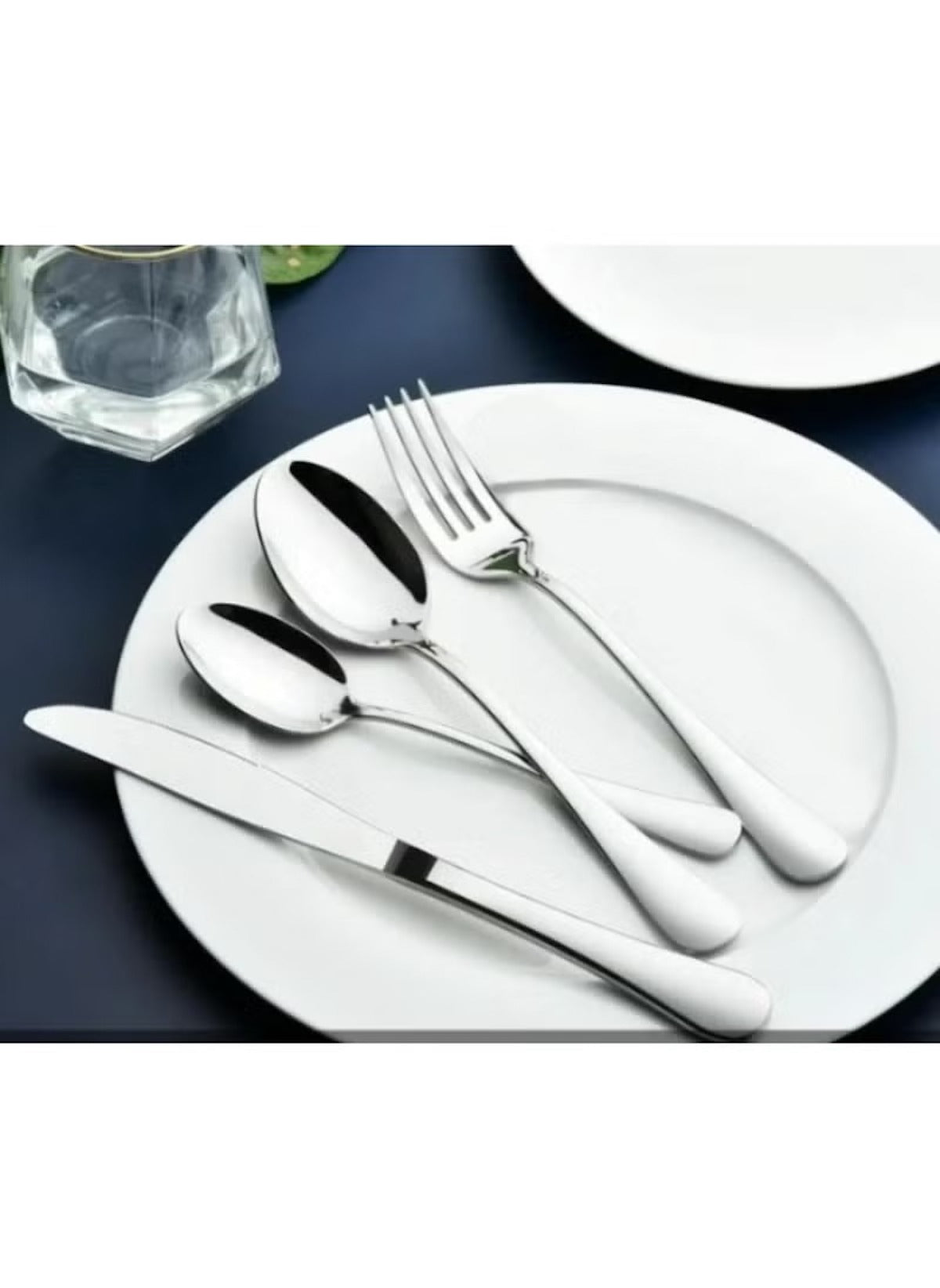 Huitich 24-piece dining flatware set with stainless steel knife fork and spoons on white plate