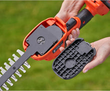 Cordless shrub shear with open battery compartment cover and comb blades, orange and black