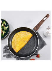 Huitich 26cm skillet for induction with wooden handle cooking a folded omelette on a gray cloth