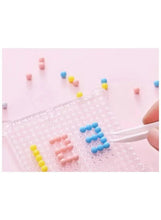 Water bead craft tray with blue and pink blocks being placed by a hand