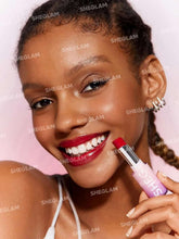Model applying dark red high-shine lipstick with tube held near lips