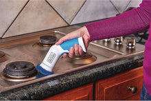 Power scrubber brush in use, held in hand with blue body and dark brush pad