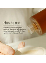 Skincare essence bottle with white cap, hand applying drops to palm
