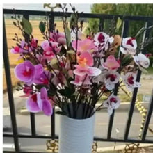 Artificial flower arrangement in white pot with pink, purple, and white orchid blooms