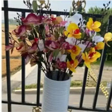 Artificial flower arrangement in white pot with purple, yellow, and pink blooms