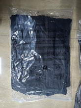 Folded black long-sleeve sports top in clear plastic bag with label