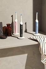 Whitening toothbrushes on a bathroom shelf with white handles and blue bristle heads