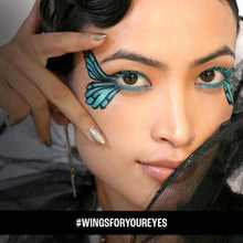 Close-up face with teal eye makeup and a hand holding a black kajal pencil near the eye