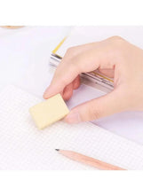 Hand holding a yellow block eraser for drawing on grid paper