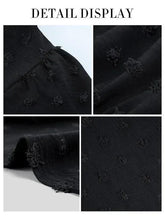 Black Swiss-dot fabric detail with textured raised embroidery sprigs
