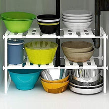 White two-tier under-sink storage rack holding stacked bowls and containers