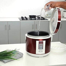 Red electric rice cooker steaming with water being poured into the inner pot