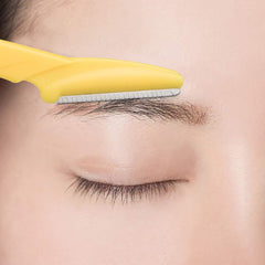Close up of a yellow eyebrow razor trimming a natural eyebrow on smooth skin eyebrow razor for women and men