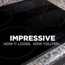 Black glass cooktop with circular burner rings and countertop edge