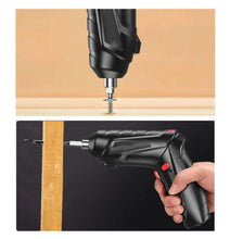 Cordless screwdriver fastening a screw into a wooden board, black body with red switch