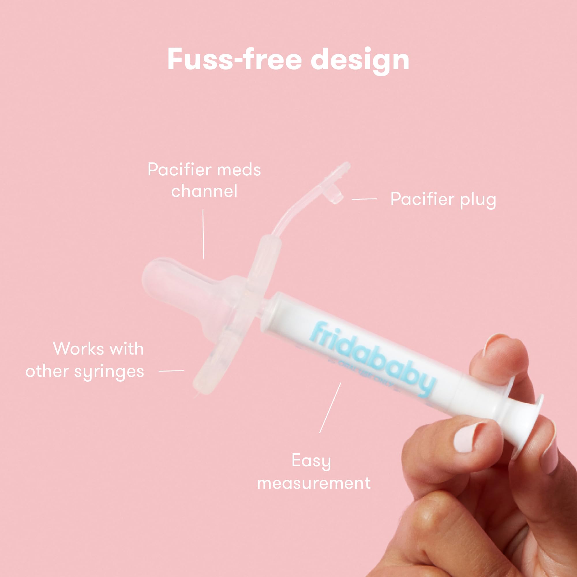 Frida Baby MediFrida Accu-Dose Pacifier held in hand on pink background showing pacifier plug and dosing syringe