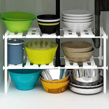 White 2-tier under-sink organizer rack with stacked bowls, cups, and colorful bins