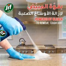 Gloved hands spraying white foam from a kitchen trigger bottle onto stove