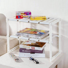 White two-tier under-sink storage rack with books and small items on shelves