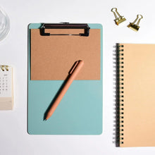 Small plastic clipboard with metal clip, cork backing panel, light teal.