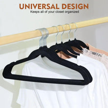 Black velvet clothes hangers with metal hooks holding white shirts on a rod