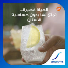 Toothpaste box with hand holding ice glass with lemon slice graphic, Arabic text