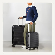 Black hard-sided spinner luggage set with one case held upright beside larger case