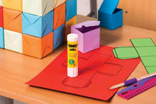 UHU stic glue stick, white tube with yellow label, on red craft paper